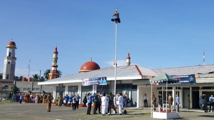 Personil Polres Aceh Selatan, Bripda Hubul Wahan memanjat tiang bendera untuk memasang tali yang putus saat berlangsungnya upacara memperingati Hari Sumpah Pemuda ke-90 Tahun 2018 di Kabupaten Aceh Selatan, Senin (29/10/2018)